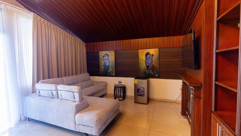 Sala acogedora con sofá claro, mesas de madera y pinturas en la pared, ubicada en Villa Shalom en Santa Rosa de Copán, Honduras.
