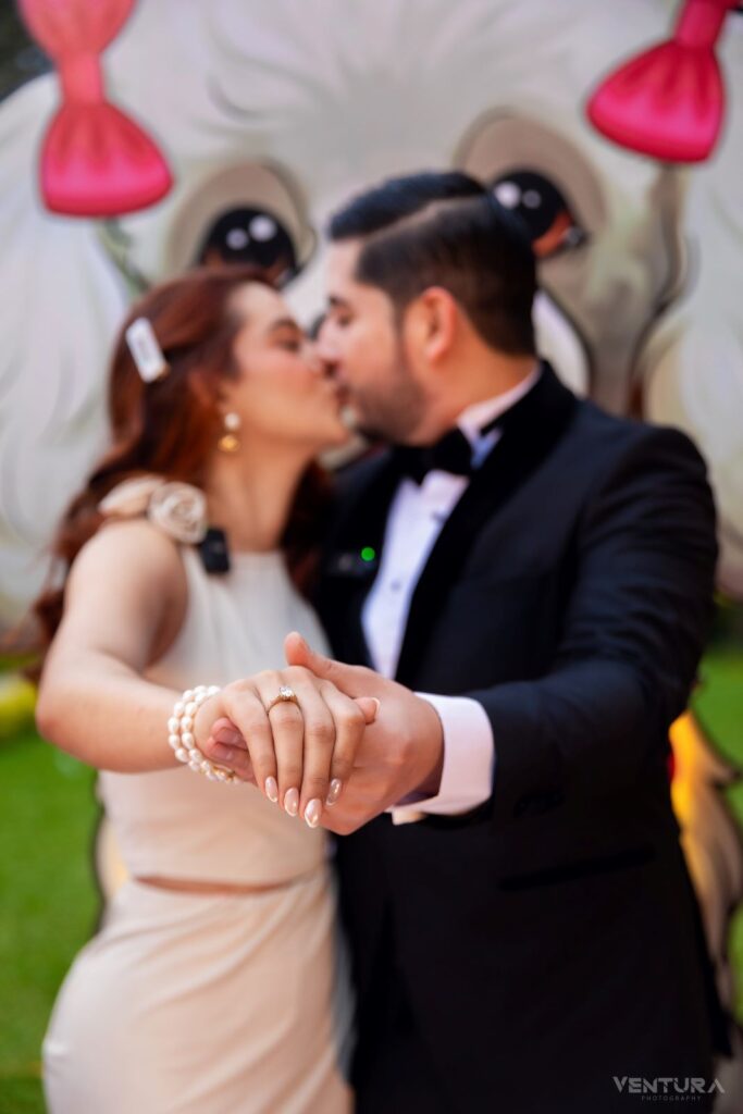 Pareja de novios besándose en un ambiente festivo, con un fondo colorido y detalles decorativos, en Villa Shalom, Santa Rosa de Copán.