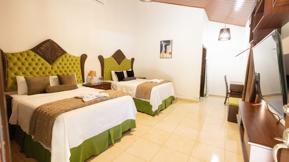 Habitación en Villa Shalom con dos camas, decoradas en tonos verdes y beige, y un ambiente acogedor y luminoso.