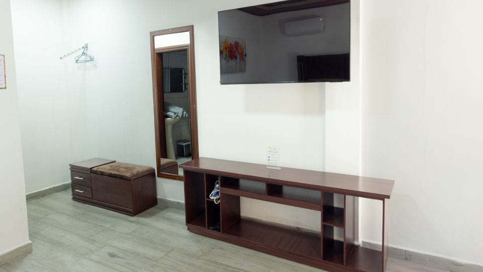 Habitación de Villa Shalom con un mueble de TV, espejo y pared clara, creando un ambiente acogedor y moderno.
