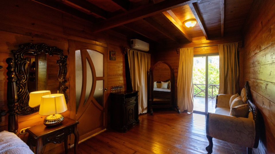 Interior acogedor de una habitación en Villa Shalom, con muebles de madera, ventana amplia y decoración cálida.