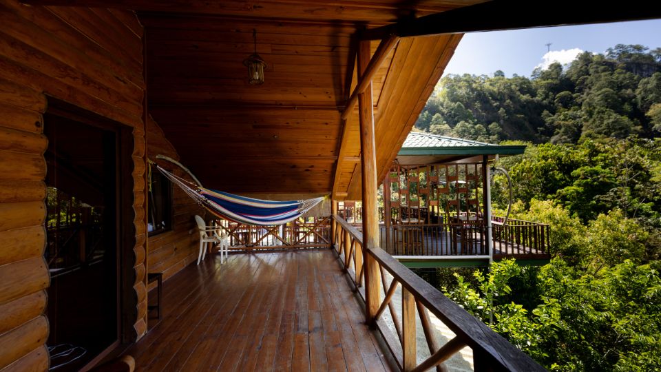 Terraza de madera en Villa Shalom, con una hamaca y vistas a la vegetación circundante en Santa Rosa de Copán, Honduras.