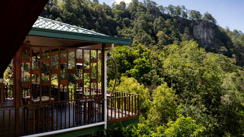 Cabaña en Villa Shalom, rodeada de vegetación exuberante y montañas, con una terraza que ofrece vistas panorámicas.