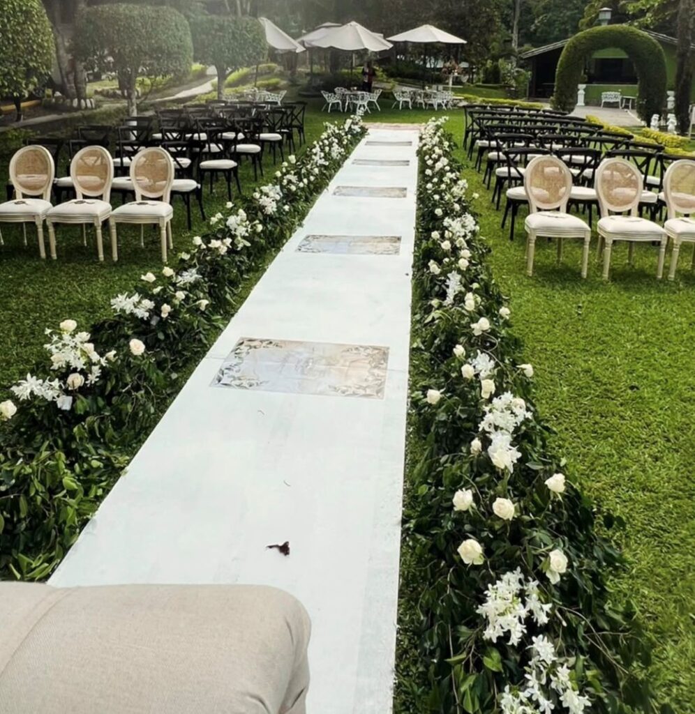 Camino decorado con flores blancas y sillas dispuestas para una ceremonia al aire libre en Villa Shalom, Santa Rosa de Copán, Honduras.