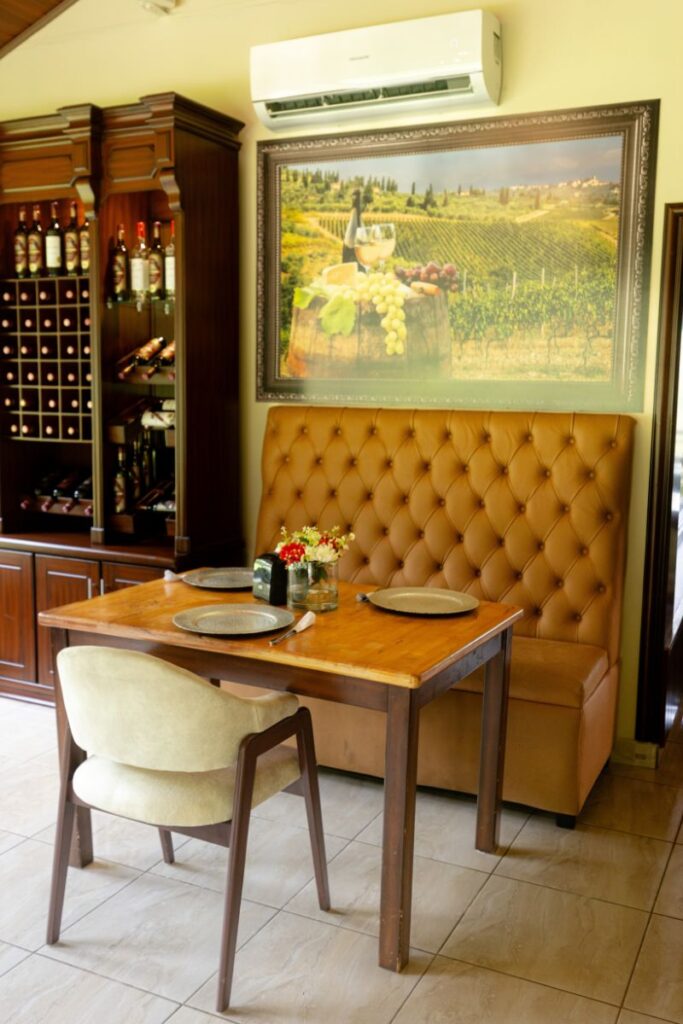Mesa para dos con vajilla elegante en el restaurante de Villa Shalom, Santa Rosa de Copán, rodeada de un ambiente acogedor y mural decorativo.