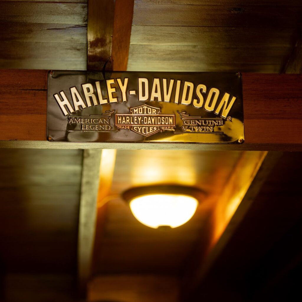 Cartel de madera con el logotipo de Harley-Davidson, colgado en el techo de un espacio acogedor.