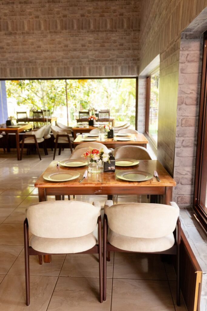Comedor del restaurante en Villa Shalom, con mesas de madera, sillas cómodas y vistas al jardín exterior.
