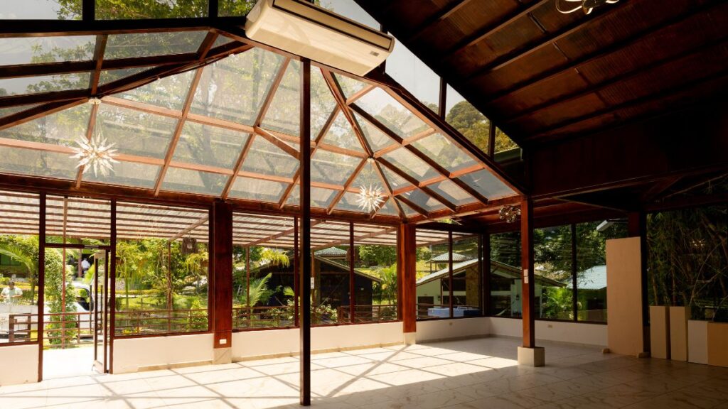 Espacio interior en Villa Shalom con grandes ventanales y estructura de madera, rodeado de naturaleza en Santa Rosa de Copán, Honduras.